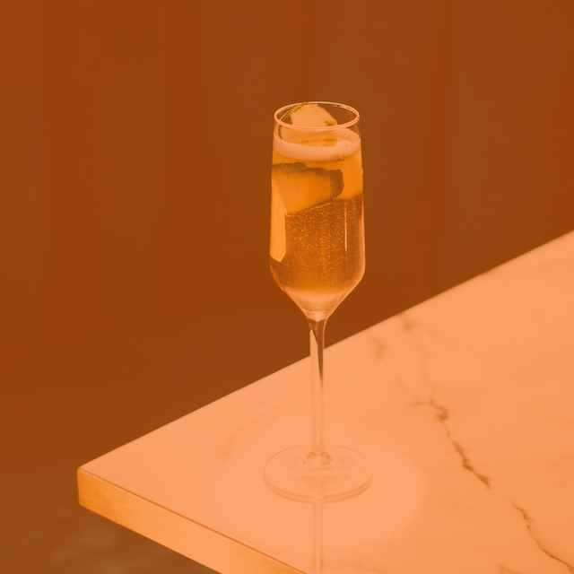 A photo of a French 75 on a counter, with an orange color overlay.