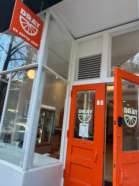 The front entry of Dray, featuring the bright orange doors (one open) and sign.