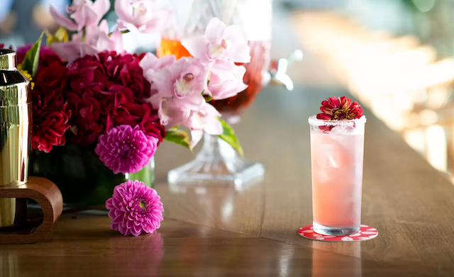 A photo of an NA cocktail surrounded by beautiful pink and purple flowers.