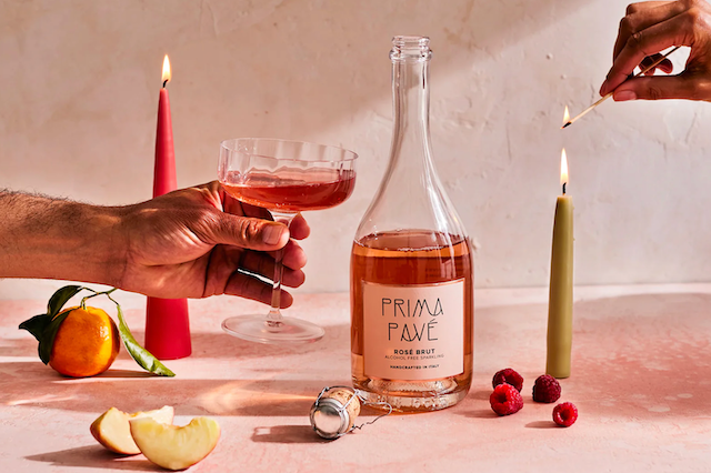 A bottle of Prima Pavel Rose Brut surrounded by candles and fruit.