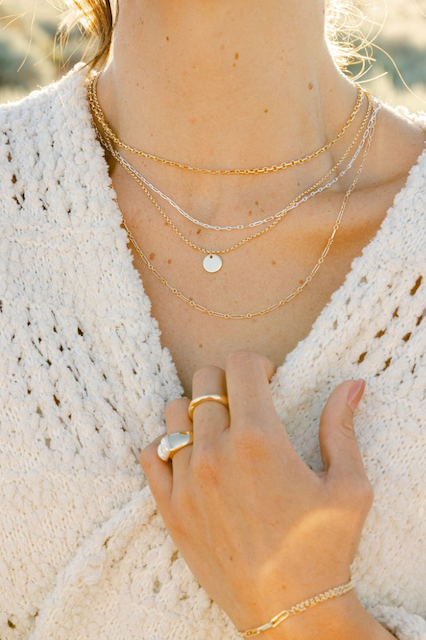 A photo of a woman showing off her claspless necklaces.